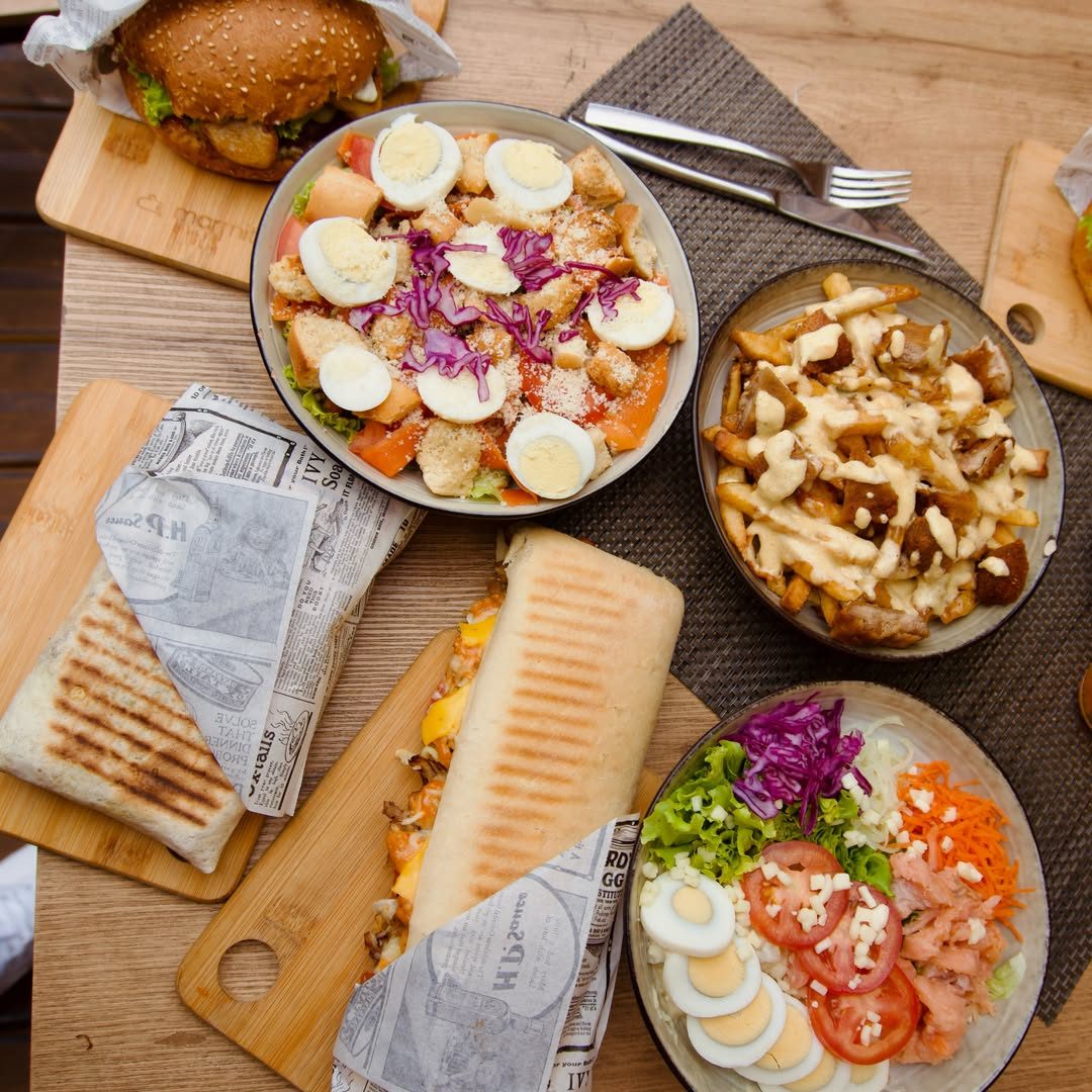 Paninis, salade César et frites sauce fromagère sur table en bois